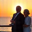 A sophisticated couple enjoying champagne on the deck of a yacht at sunset, looking relaxed and content.