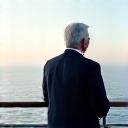 A single discerning traveler, looking out at the ocean from a luxurious yacht deck, embodying a luxury travel enthusiast.